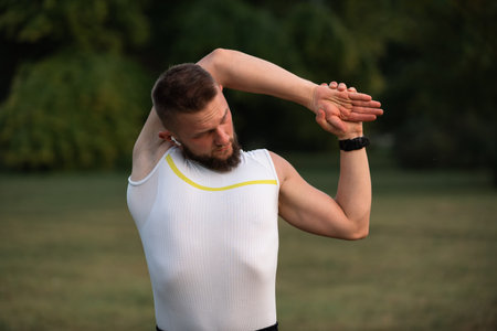 A young fit man doing stretching exercises before running or workout in a park. Active lifestyle, fitness and outdoor exercise concept.の写真素材