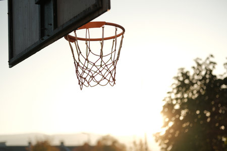 A basketball hoop at an outdoor court captured in the warm light of sunset. The minimalist and...
