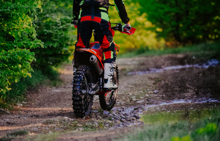 Professional enduro bike rider dirt ride on the muddy road. Motocross sport.