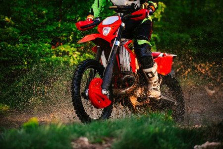 Professional enduro bike rider on action, dirt ride on the muddy track. Motocross sport.