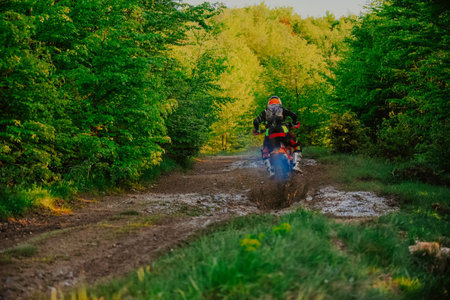 Professional enduro bike rider on action, dirt ride on the muddy track. Motocross sport.