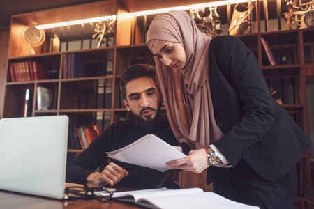 A business team of young man and Muslim woman working together on the project planning strategy in the modern office or Arabic college students study together in the library on the university campus.の写真素材