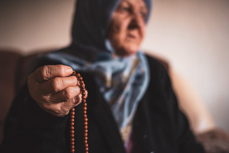 The old Muslim woman holds the rosary in her hands, doing zikr pray with traditional prayer beads.の写真素材