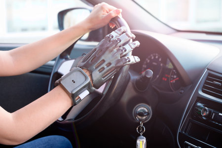 A girl with a prosthetic arm drives a car. The concept of a full life for people with disabilities. Side view, small depth of field.の写真素材