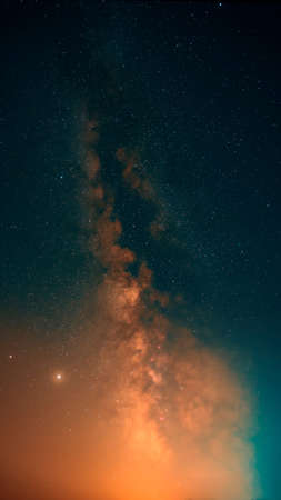 vertical photo of the milky way galaxy in turquoise orange colorsの写真素材