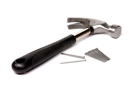 A hammer with a black handle and nails lies diagonally on a white isolated background.の写真素材