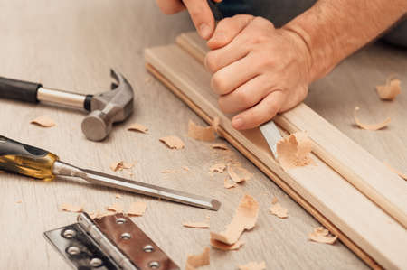 Installing the door hinge on the door frame with your own hands using a hand tool, close-up.の写真素材