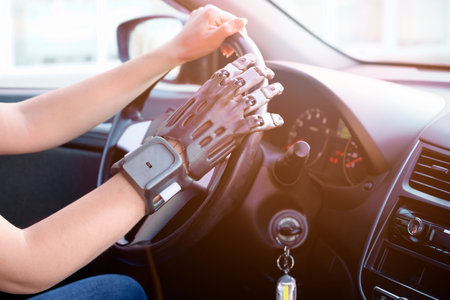 A person with a prosthetic hand printed on a 3d printer at the wheel of a car. Concept of practical application of 3D printing.の写真素材