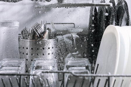 Dishes are washed in the dishwasher a lot of water splashes, close-up view from the inside selective focusの写真素材