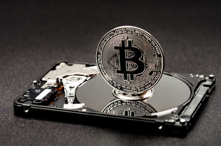 Bitcoin on a hard disk on a black background, the concept of mining cryptocurrencies using hard and SSD drives.の写真素材