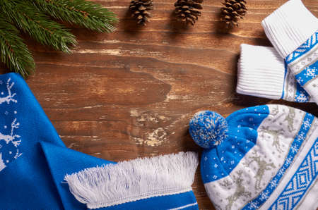 Fir branch with cones, warm mittens, a scarf and hat on a vintage wooden background.の写真素材