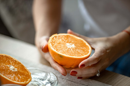 an orange is cut in half in the hands of a womanの写真素材