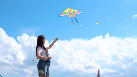 A, young, pregnant, girl, jumpsuit, launches, kite, against, blue, sky, clouds.の写真素材
