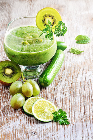 Refreshing green detox smoothie with cucumber, apple, grapes and kiwi on wooden backgroundの写真素材