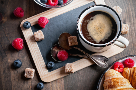 Coffee, croissants with raspberries and bluererries for breakfast. Toned image, selective focus, top viewの写真素材