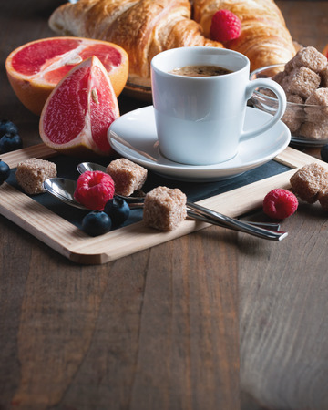 Coffee and croissants with raspberries and fruits for breakfast. Chalk board. Toned image, selective focusの写真素材