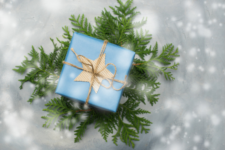 Christmas gift box in blue wrapping paper. Copy space. Toned image, falling snow effect.の写真素材