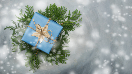 Christmas gift box in blue wrapping paper. Copy space. Toned image, falling snow effect.の写真素材
