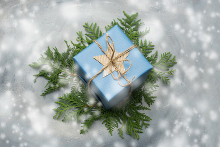 Christmas gift box in blue wrapping paper. Copy space. Toned image, falling snow effect.の写真素材