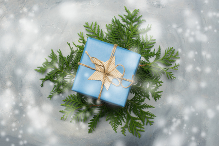 Christmas gift box in blue wrapping paper. Copy space. Toned image, falling snow effect.の写真素材