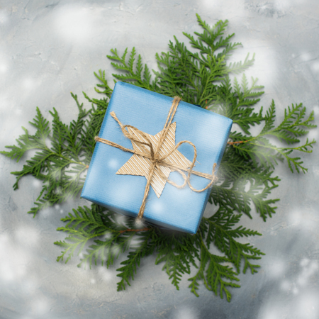 Christmas gift box in blue wrapping paper. Copy space. Toned image, falling snow effect.の写真素材