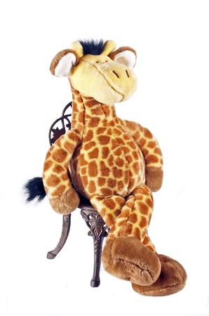 Toy giraffe sitting on old garden chair isolated on whiteの写真素材