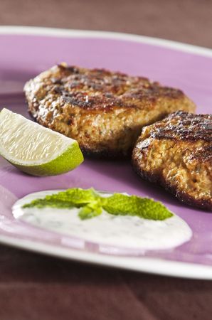 Lamb shami kebabs served on lilac plate with yogurt and mint sauceの写真素材