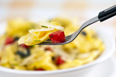 Tortellini primavera garnished with basil leaves on white plateの写真素材