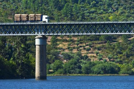 Big truck with lumber moving across bridgeの写真素材