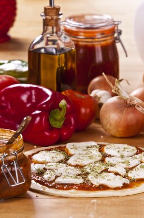 preparing a pizza pie on a wooden kitchen tableの写真素材