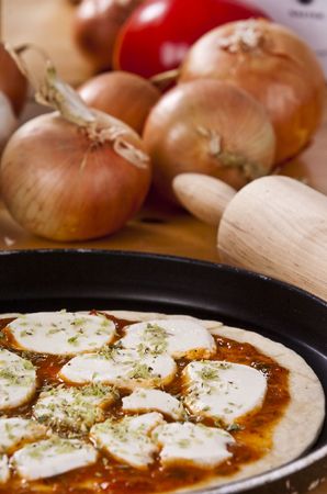 preparing a pizza pie on a wooden kitchen tableの写真素材