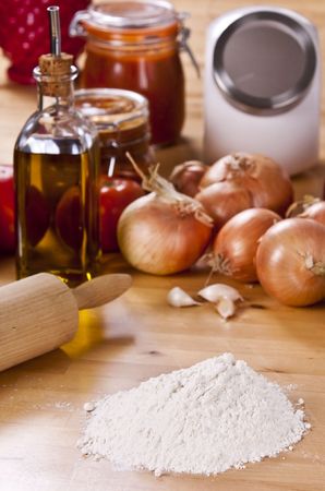 preparing a pizza pie on a wooden kitchen tableの写真素材
