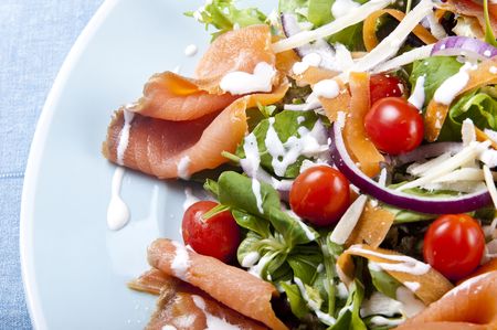 Fresh smoked salmon salad with lettuce tomato and dressingの写真素材