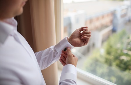 close up of a hand man how wears white shirt and cufflink. window wiev