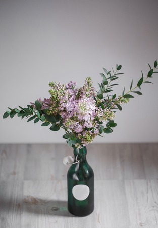 Lilac flower in a green vase on a wooden backgroundの写真素材