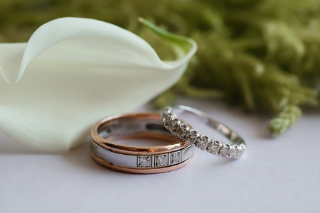 wedding rings on table with calla lilies and greens.の写真素材