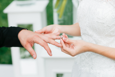 Close-up of a bride putting a wedding ring on a groomの写真素材