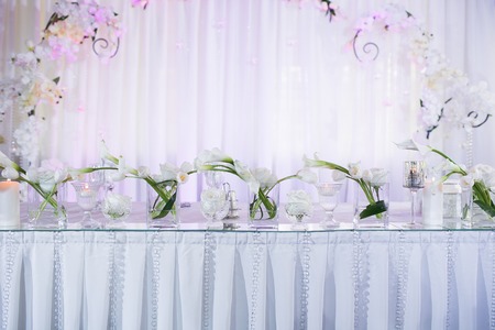 Beautiful restaurant interior table decoration for wedding. Flower Wedding Table Decoration. White calla lilies and tulips in vases. Candles.の写真素材