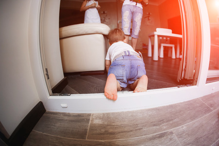Little baby crawling to his father staying on terrace. playing at home.の写真素材