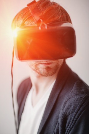 Handsome man wearing virtual reality glasses isolated on a gray background.の写真素材