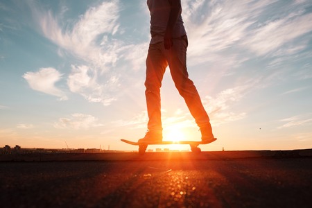Young skaters training in the park in sunset. Birds. Blue skyの写真素材
