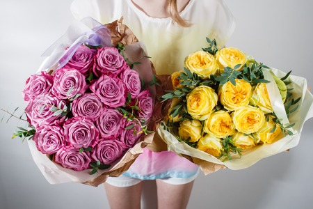 bouquet of roses in hands of the florist.. Color pink and yellow. in kraft packagingの写真素材