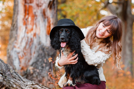 Young woman playing with black puppy in the autumn forest.の写真素材