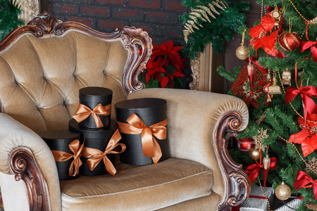 Wrapped gift black boxes with ribbons as Christmas presents on a chair.