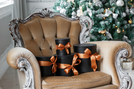 Wrapped gift black boxes with ribbons as Christmas presents on a chair.