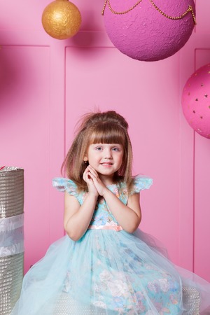 Pretty girl child 4 years old in a blue dress. Baby in Rose quartz room decorated holidayの写真素材
