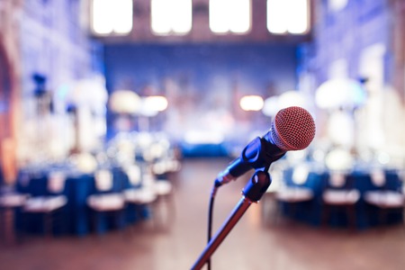 Microphone over the Abstract blurred photo of conference hall or wedding banquet backgroundの写真素材