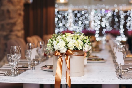 hat box with flowers close-up. Wedding. Banquet. The chairs and table for guests, served with cutlery and crockery.の写真素材