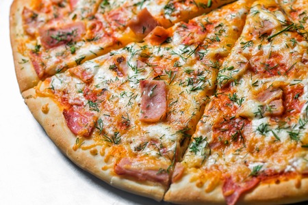 pizza with ham, by cut to pieces on a metal table. selective focus on the filling close-up.の写真素材