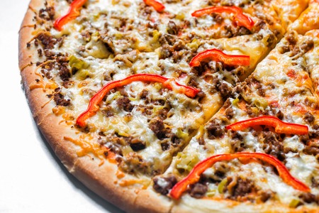 pizza with minced meat and peppers, by cut to pieces on a metal table. selective focus on the filling close-up.の写真素材